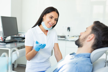 female smiling dentist talking with male client in hospital