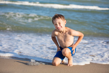 A boy on the beach is playing with a jellyfish. Child resting on the beach