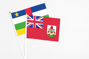 Fototapeta premium Bermuda and Central African Republic stick flags on white background. High quality fabric, miniature national flag. Peaceful global concept.White floor for copy space.