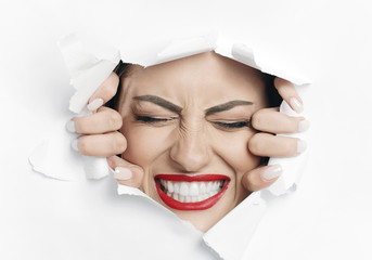 Young beautiful woman is struggling to break through a white material wall