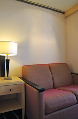 Couch sofa and side table with lamp light inside cabin stateroom suite room on luxury cruise ship...