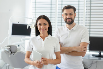 portrait of young male and female dentists looking at camera in dental office