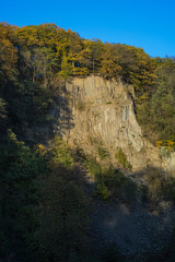 Rock wall at the Weilbergsee with autumn forest in the evening light.