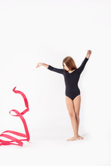 girl gymnast trains with a gymnastics tape on white background. children's professional sports.