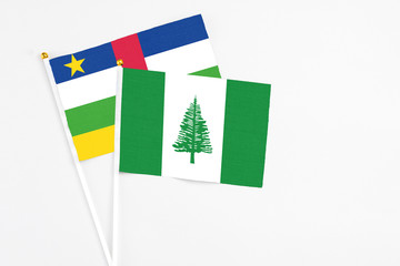 Fototapeta premium Norfolk Island and Central African Republic stick flags on white background. High quality fabric, miniature national flag. Peaceful global concept.White floor for copy space.
