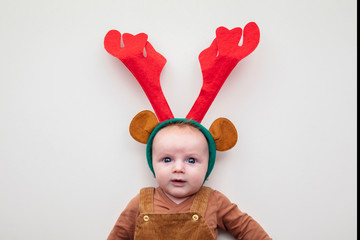 A cute two month old baby wearing festive christmas reindeer antlers