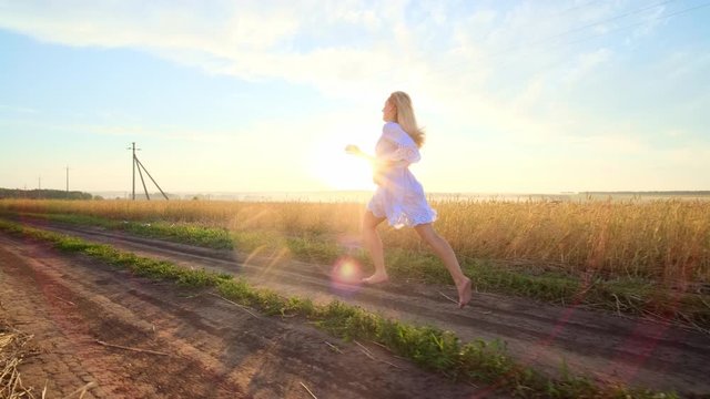 Beauty girl running on yellow wheat field. Freedom concept. Happy woman outdoors. Harvest.