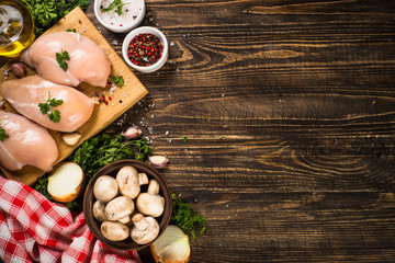 Chicken fillet with ingredients for cooking on wooden table.