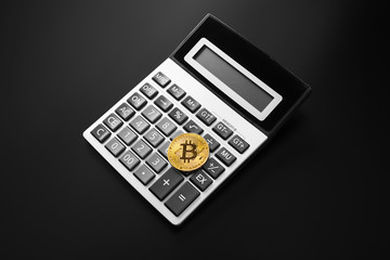 golden bitcoin coin on calculator close up isolated on black background