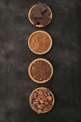 organic cacao beans, cocoa powder, ground and chocolate on a black background with copy space for text. Flat lay, top view. Ingredient. Vegan food. Background, pattern, card, menu. Vertical photo.
