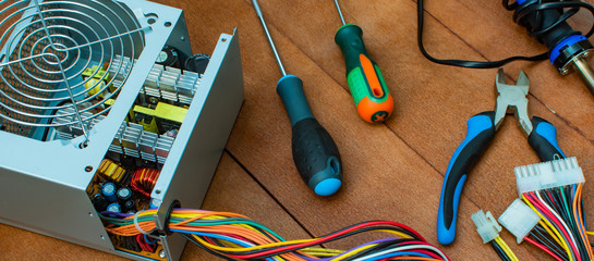 disassembled desktop PC power supply with desktop repair tools.