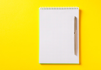 the white open notepad on silver pen isolated on the yellow background