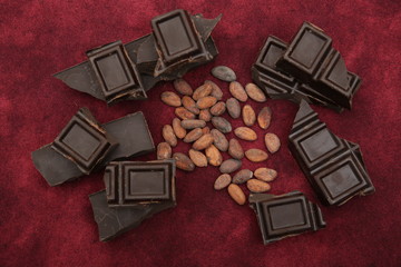 dark bitter chocolate with organic cocoa beans on a red background. Confectionery ingredient. Background, pattern, postcard, menu. Flat lay. Top view.