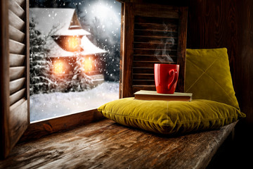 Winter wooden old retro window sill and pillows.Free space for your decoration and christmas time.Small home cover of snow and frost and moon on sky.December time and snowflakes.Dark forest landscape