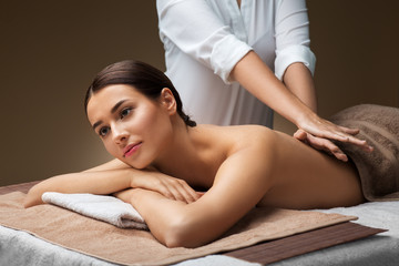 wellness, beauty and relaxation concept - beautiful young woman lying and having back massage at spa