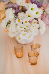 Coziness and style. Modern event design. Table setting at wedding reception. Floral compositions with beautiful flowers and greenery, candles, laying and plates on decorated table.