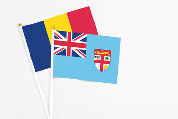 Fototapeta premium Fiji and Chad stick flags on white background. High quality fabric, miniature national flag. Peaceful global concept.White floor for copy space.