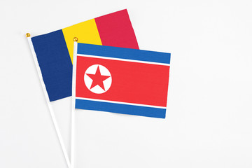 North Korea and Chad stick flags on white background. High quality fabric, miniature national flag. Peaceful global concept.White floor for copy space.