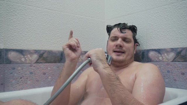 weekend at home.strange hobbies and inclinations.funny emotional middle aged man singing in the shower while sitting in the bathroom