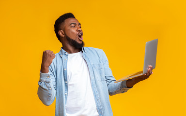 Ecstatic black guy watching football online on laptop