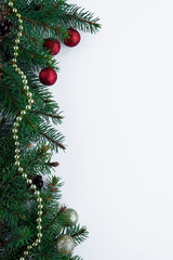 Fototapeta na wymiar Christmas decorations: green spruce tree branches, little red and gold baubles and chain. Festive vertical greeting card with copy space for text.