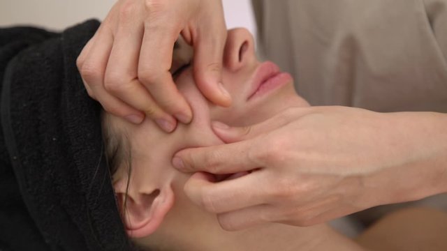 Spa woman facial Massage. Face Massage in beauty spa salon. Female enjoying relaxing face massage in cosmetology spa centre.