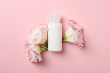 Beautiful flowers and blank bottle on pink background, space for text