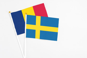 Sweden and Chad stick flags on white background. High quality fabric, miniature national flag. Peaceful global concept.White floor for copy space.