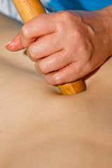 Wellness concept. Professional masseur gives a man a Thai massage with bamboo sticks at the spa. Relaxation and recovery after work.
