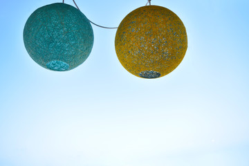 Two hanging paper lanterns for a party with a blue sky background.