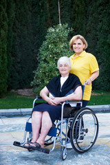 Obraz premium Volunteer caregiver and handicapped senior woman, outdoors