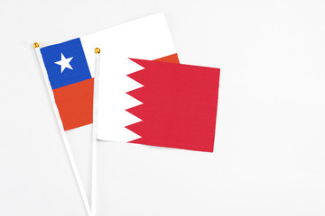 Bahrain and Chile stick flags on white background. High quality fabric, miniature national flag. Peaceful global concept.White floor for copy space.