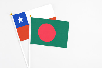 Bangladesh and Chile stick flags on white background. High quality fabric, miniature national flag. Peaceful global concept.White floor for copy space.