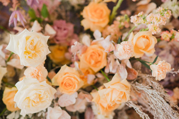 Coziness and style. Modern event design. Table setting at wedding reception. Floral compositions with beautiful flowers and greenery, candles, laying and plates on decorated table.