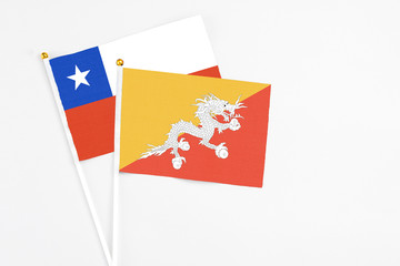 Bhutan and Chile stick flags on white background. High quality fabric, miniature national flag. Peaceful global concept.White floor for copy space.