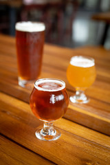 IPA in a tulip glass on a wood bar counter, with beers in background