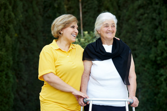 Volunteer caregiver and handicapped senior woman, outdoors