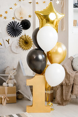 Birthday decorations with gifts, toys, balloons, garland and figure 1 for little baby party on a white wall background.