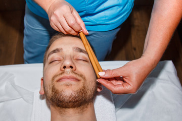 Wellness concept. Professional masseur gives a man a Thai facial massage with special sticks in a spa center. Relaxation and recovery after work.