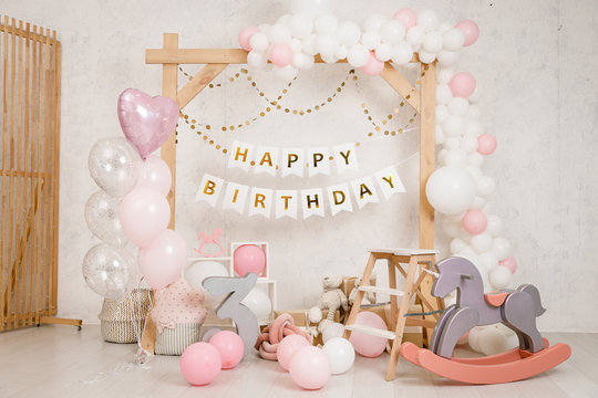 Birthday decorations - gifts, toys, balloons, garland and number for little  baby party on a white wall background. Stock Photo