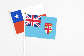 Fototapeta premium Fiji and Chile stick flags on white background. High quality fabric, miniature national flag. Peaceful global concept.White floor for copy space.