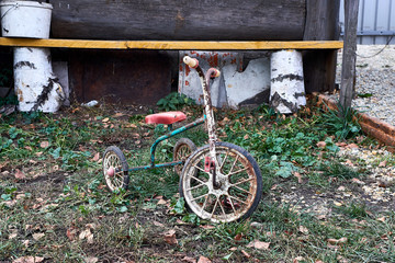 An antique kids tricycle with fading red paint isolated over white background
