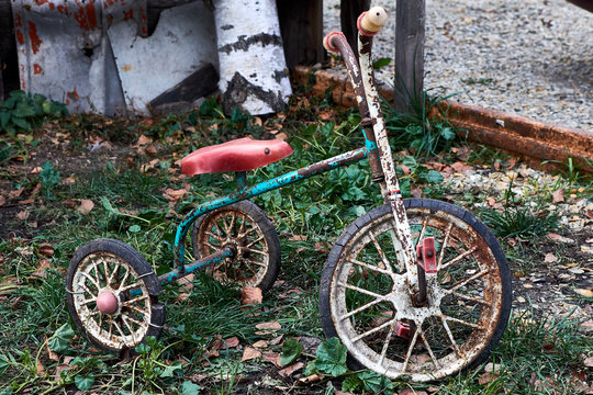 An antique kids tricycle with fading red paint isolated over white background