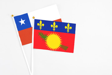 Guadeloupe and Chile stick flags on white background. High quality fabric, miniature national flag. Peaceful global concept.White floor for copy space.