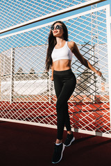 Beautiful fitness woman in sportswear posing near grid.