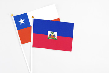Haiti and Chile stick flags on white background. High quality fabric, miniature national flag. Peaceful global concept.White floor for copy space.