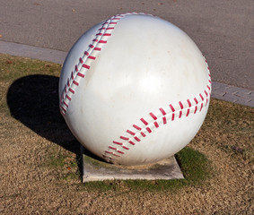 Huge outdoor decorative concrete baseball with red cement stitching .