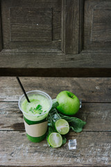 Green apple smoothie in glass and kale leaves on wooden table - 302508646