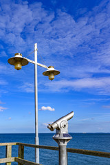 Telescope with coin slot and lantern on the pier in Bansin on the island of Usedom in Germany. Sea...