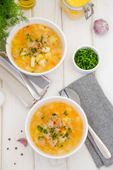 Homemade soup with vegetables, canned tuna and corn grits in a bowl on a white wooden background. A quick, cheap lunch for the whole family.